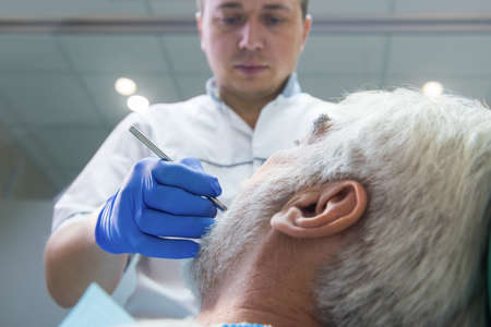Dentist working with elderly patient. Hand of doctor in glove.の写真素材