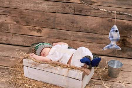 Baby fisherman is sleeping. Kid, hay and wood background. How to start fishing.の写真素材