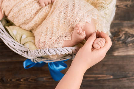 Hand holding foot of child. Little kid wrapped in blanket. Joy of having a baby.