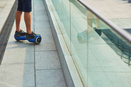 Male legs on hoverboard. Person riding gyroscooter outdoors. Self balancing scooter safety guide.の写真素材