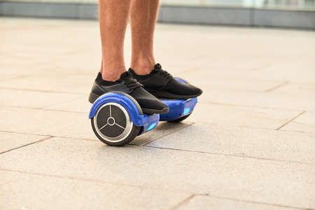 Legs on hoverboard. Blue gyroscooter, pavement background. Mini segway for sale.の写真素材