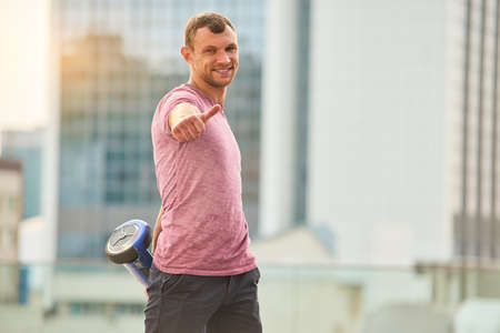 Young man showing thumb up. Guy holding a hoverboard.