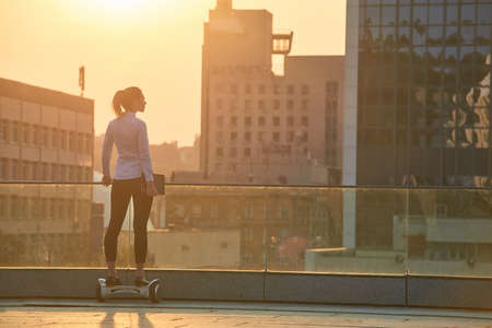 Woman on hoverboard, urban background. Businesswoman with tablet. World of possibilities.の写真素材