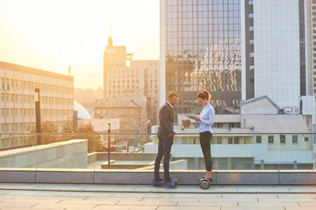 Business people in the city. Woman and man on hoverboards.の写真素材