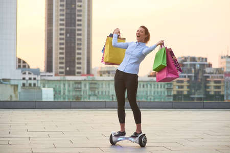 Happy woman holding colorful bags. Cheerful female in the city. How to make shopping fun.