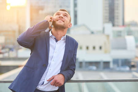 Businessman with phone looking up. Young male outdoor. Keep motivated and stay inspired.の写真素材