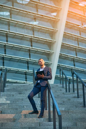 Businessman holding clipboard. Guy standing on stairs. Key steps to project management.の写真素材
