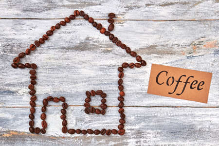 Coffee beans and message. House from coffee, wooden table.の写真素材