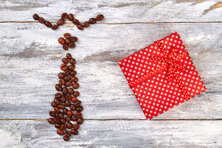Red box and coffee tie. Coffee beans figure, wooden table.