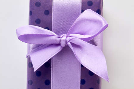 Cropped picture of gift box. Purple ribbon on violet box, white background.の写真素材