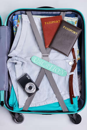One part of opened suitcase. Passports, camera, clothes in travel bag. Concept of vacation.の写真素材
