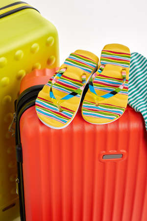 Colorful sandals on red suitcases. Clothes and wheeled suitcases, cropped image.の写真素材