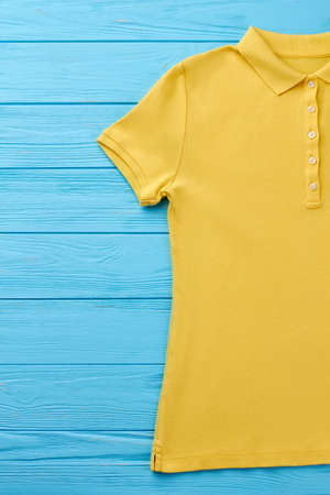 Cropped image of polo t-shirt. Summer fashion clothing for men, blue wooden background.の写真素材