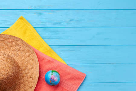 Colored towels, straw hat, globe. Concept of beach resort, blue wooden surface.の写真素材