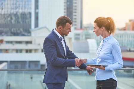 Business couple shaking hands. Young caucasian people, city. What is cooperation.の写真素材