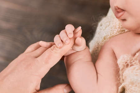 Infant holding female finger. Arm of a baby. Grasp reflex definition.の写真素材