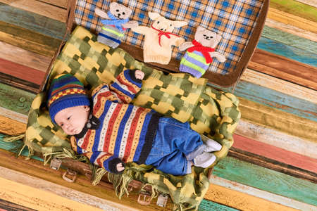 Baby in colorful sweater. Suitcase with child, top view.の写真素材