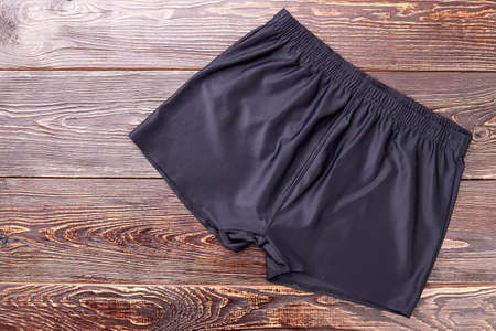 Black running shorts, wooden background. Casual shorts for athletic activity.の写真素材