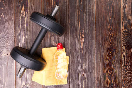 Dumbbell, towel, bottle, top view. Sport equipment in gym on wooden floor.の写真素材