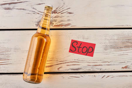 Hopelessness is not reason to drink. Bottle of lager, old wooden table.の写真素材