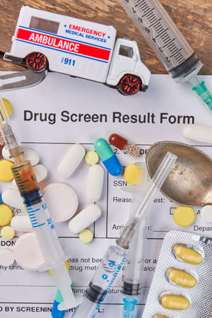 Drug screen result form, ambulance, syringes. Drugs injections and medical hospitalization. Analysis on narcotics overdose.の写真素材