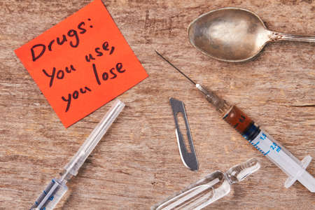 Syringes, ampoules, spoon, message. Drugs: you use, you lose.の写真素材