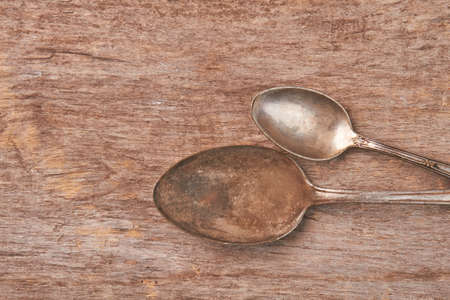 Vintage rusty spoons on wooden background. Retro tea spoons close up.の写真素材