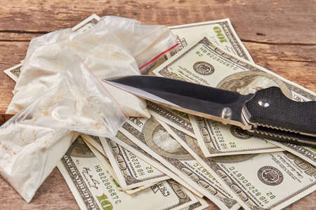 Packets with drugs, money, knife. Bags with cocaine, amount of dollars, knife close up. Use of narcotics is dangerous crime.の写真素材