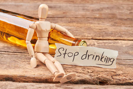 Stop drinking message, wooden dummy. Wooden puppet, transparent bottle, wooden background.の写真素材