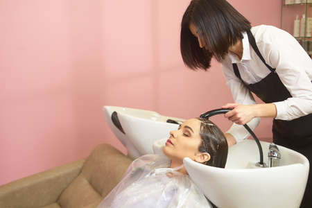 Girl getting her hair washed. Female beautician at work.