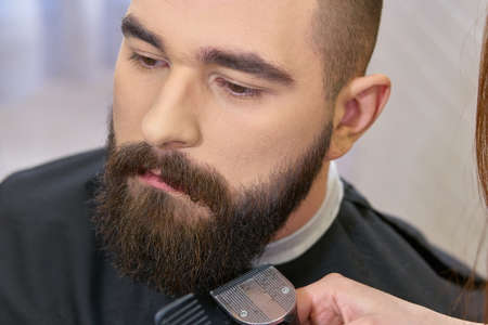 Close up of beard grooming. Barber using trimmer.の写真素材