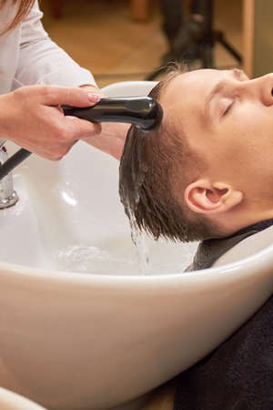 Guy getting his head washed. Barber rinsing hair of client.の写真素材