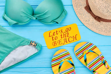 Beach accessories around paper message. Beach clothing collection, wooden background.の写真素材