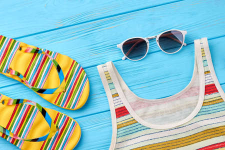 Feminine summer background. Striped slippers and shirt, sunglasses, blue wooden background.の写真素材