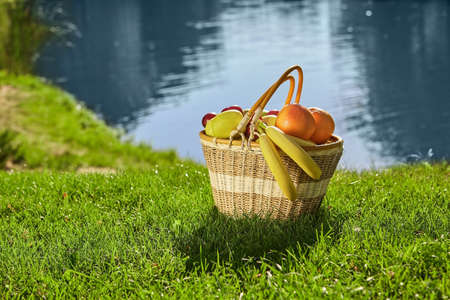 Picnic basket on green lawn. Fresh bananas and oranges. Benefits of eating healthy food.の写真素材