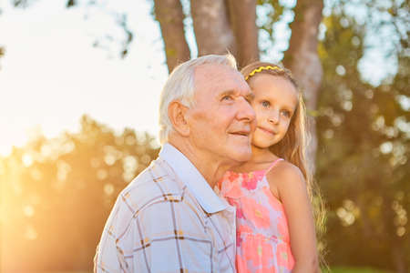 Senior man with his granddaughter. Child and grandpa outdoors. Benefits of getting older.の写真素材