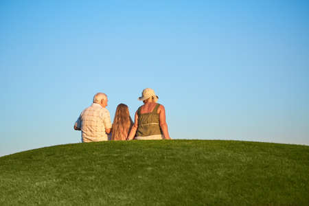People, grass and sky. Girl with grandmother and grandfather.の写真素材