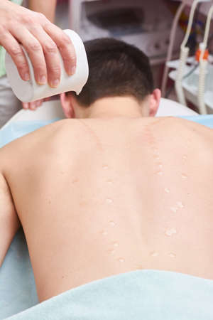 Massage oil drops on skin. Back of healthy man,の写真素材