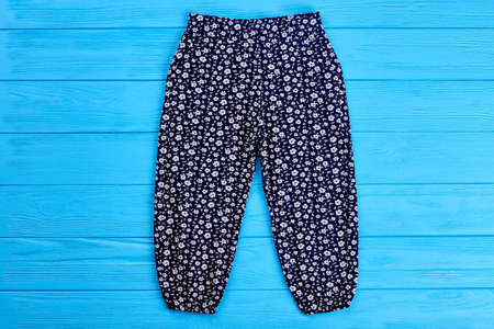 Baby girl dark blue pants. Fashionable pants for baby girl on blue wooden background. Kids fashion harems.の写真素材