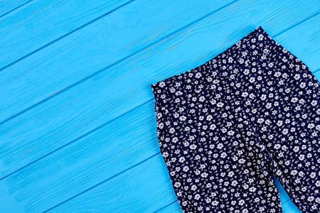 Baby girls pants, copy space. Top view of kids summer trousers on wooden background.の写真素材