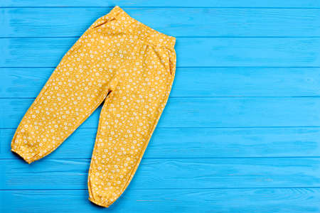 Colored trousers for baby-girl. Top view of baby girl summer pants and blue copy space. Fashionable clothing for kids.の写真素材
