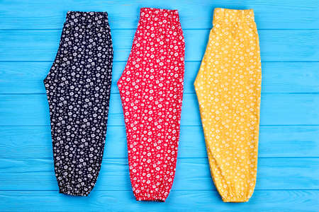 Set of colored baby girl pants. Three pairs of colorful summer trousers for little girls on wooden background, top view.の写真素材