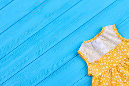 Summer sleeveless dress for little girls. Newborn baby natural clothing and copy space. Yellow baby dress with small flowers, top view.の写真素材