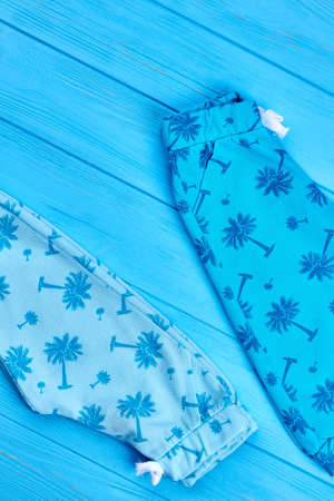 New kids fashion summer clothes. High quality casual baby summer trousers, top view. New infant childs garment on blue wooden background.の写真素材