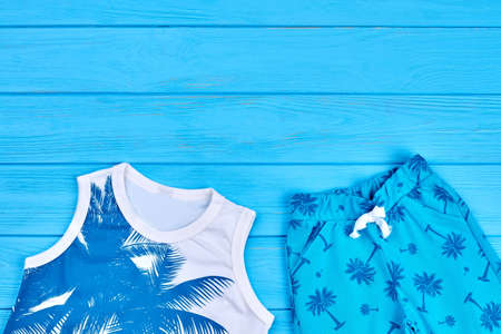 Cute unisex kids summer clothing close up. Childs summer clothes in blue tone on blue wooden background.の写真素材