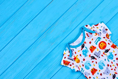 Newborn printed romper and copy space. Vintage print bodysuit for newborn on blue wooden background.の写真素材