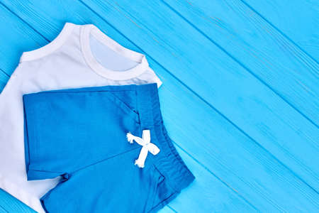 Baby boy cotton colored suit. Organic infant boy summer clothes for on blue wooden background, copy space.の写真素材