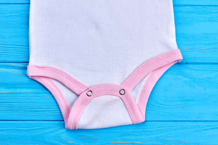 Baby-girl bodysuit close up. Cropped image of infant baby cotton romper in detail, blue wooden background.の写真素材