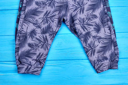 Toddlers printed pants. Baby cotton patterned trousers on blue wooden background. Kids fashion clothes.の写真素材