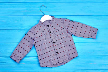 Baby boy grey dotted cotton shirt. New fashionable kids wear on blue wooden background. New cotton apparel for baby-boy.の写真素材